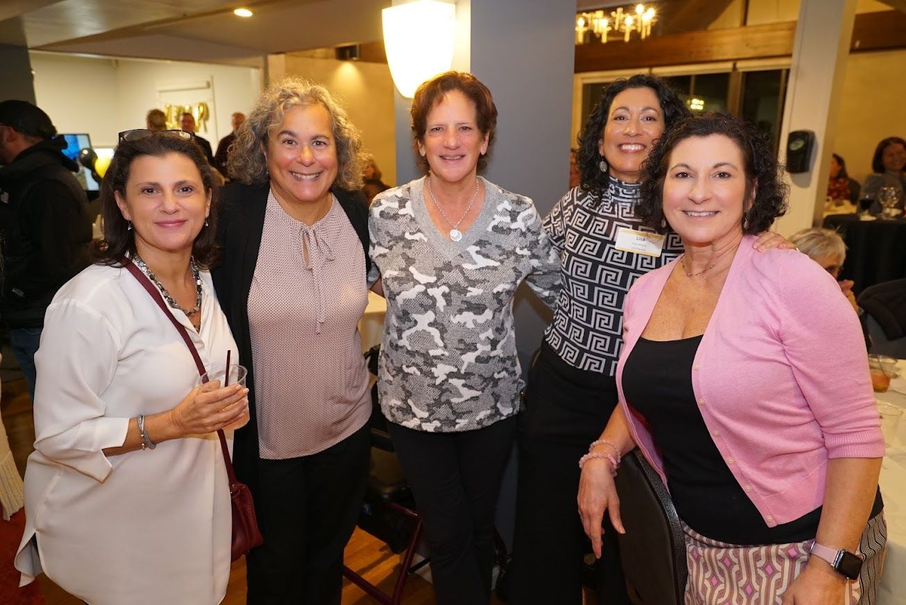 A group of women are posing for a picture together in a room.