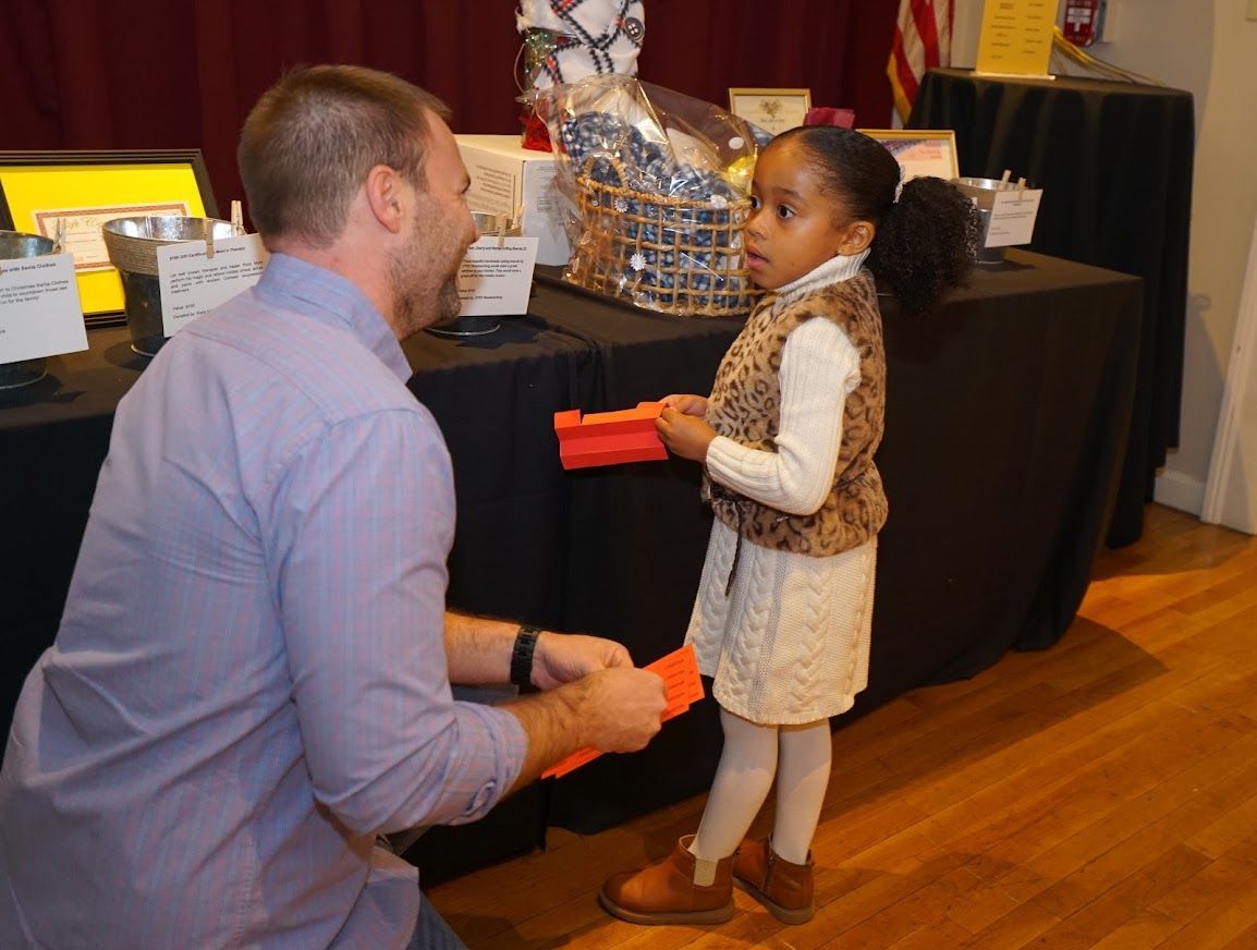 A man and a little girl are standing in front of a table.