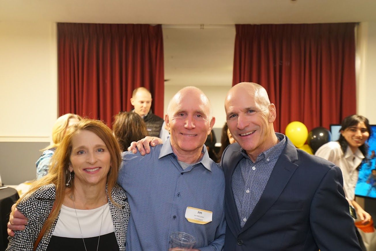 Three men and a woman are posing for a picture at a party.