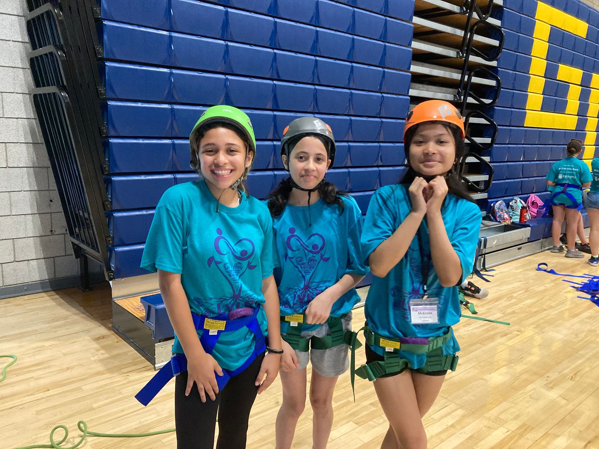 Three young girls wearing helmets are posing for a picture in a gym.