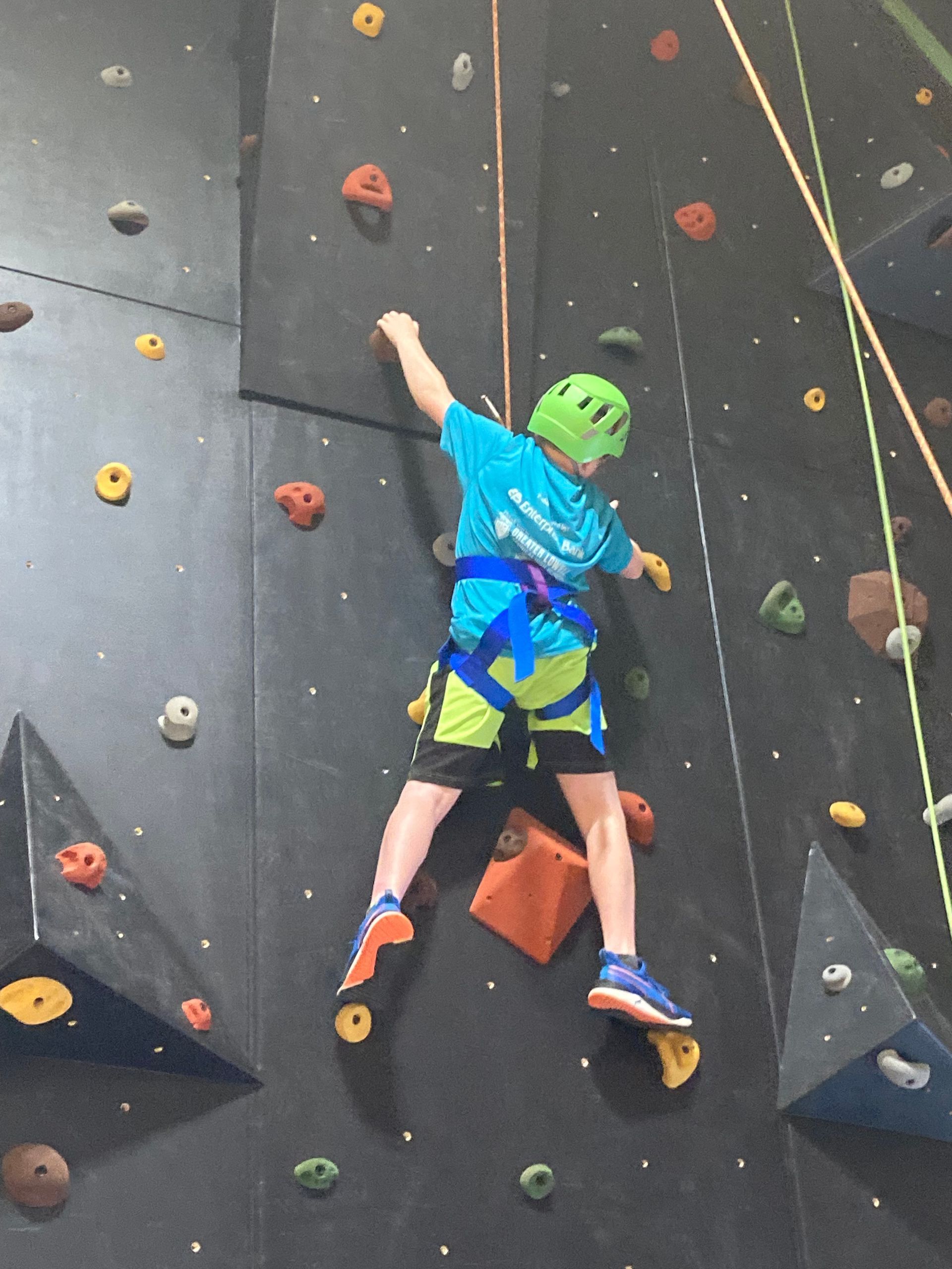 A young boy is climbing up a climbing wall