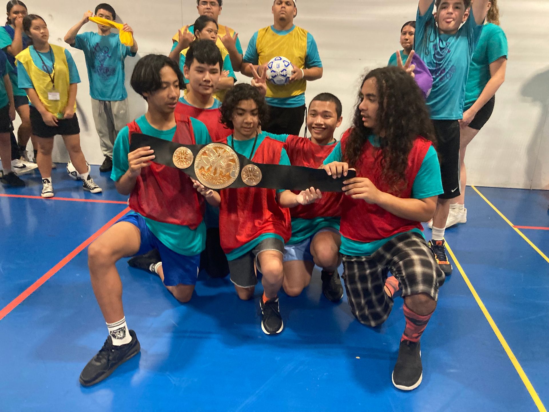 A group of young people are posing for a picture on a basketball court.