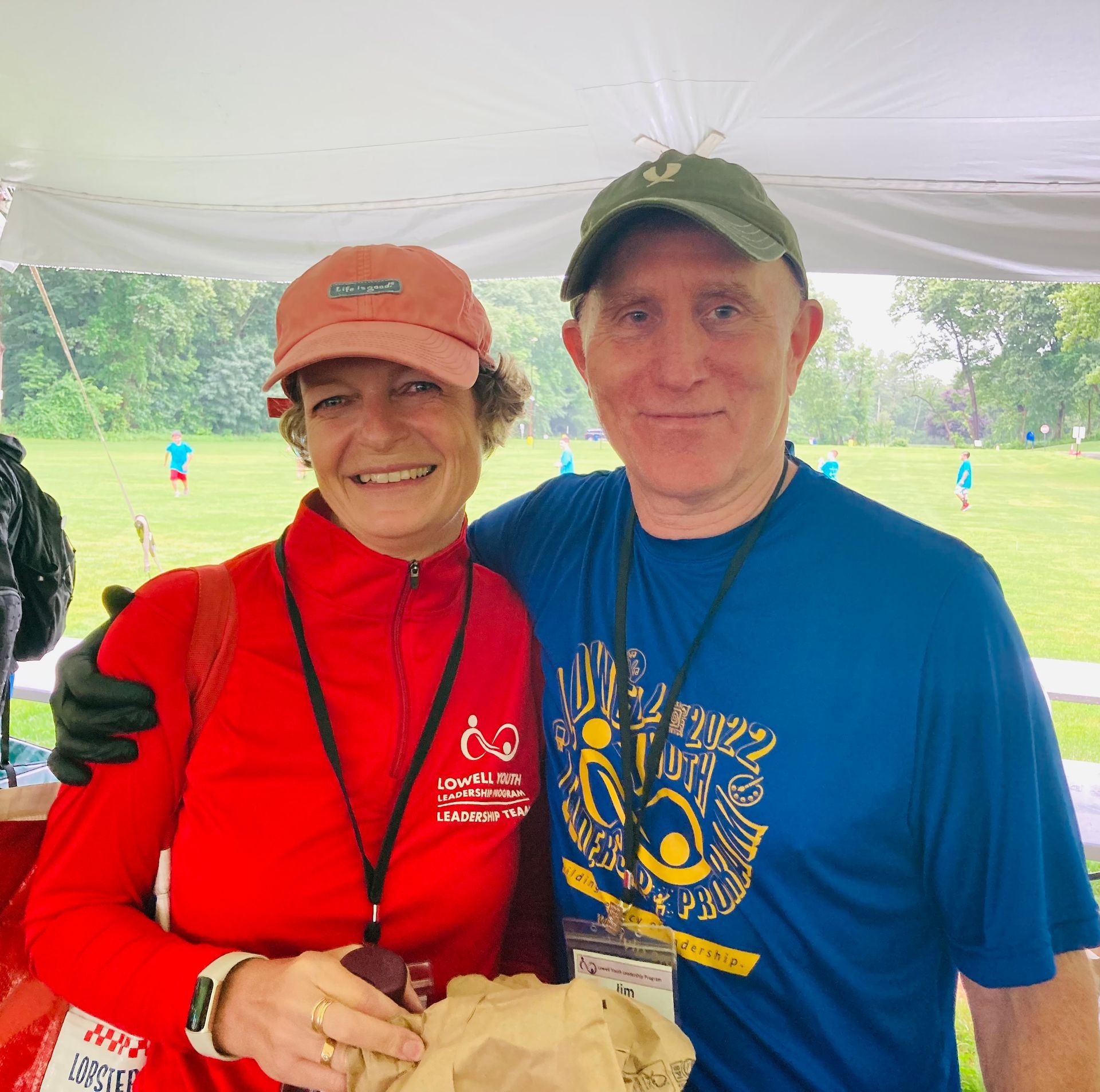 A man and a woman are posing for a picture under a tent