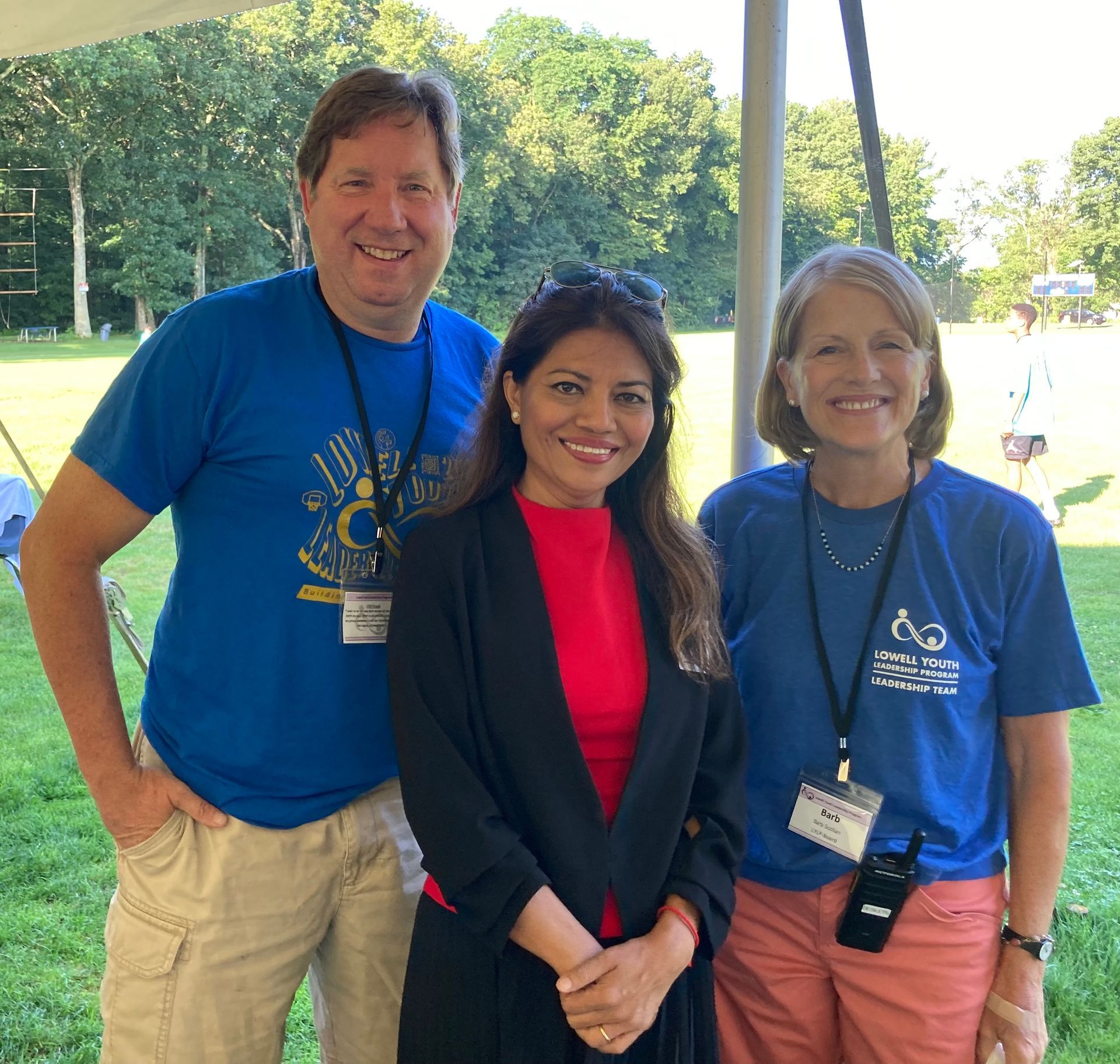 A man in a blue shirt is standing next to two women in blue shirts