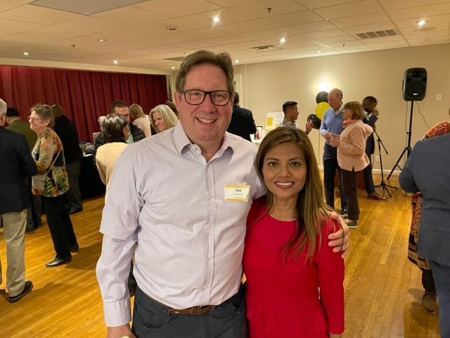 A man and a woman are posing for a picture in a crowded room.