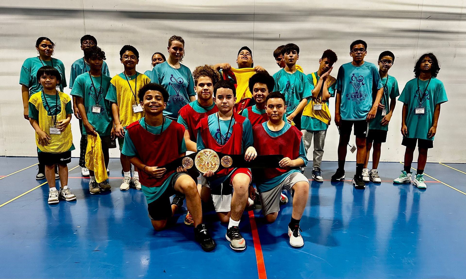 A group of young men are posing for a picture on a basketball court.