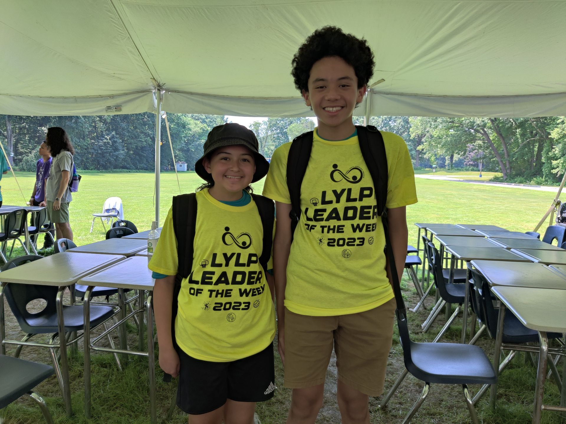 A boy and a girl are posing for a picture under a tent.