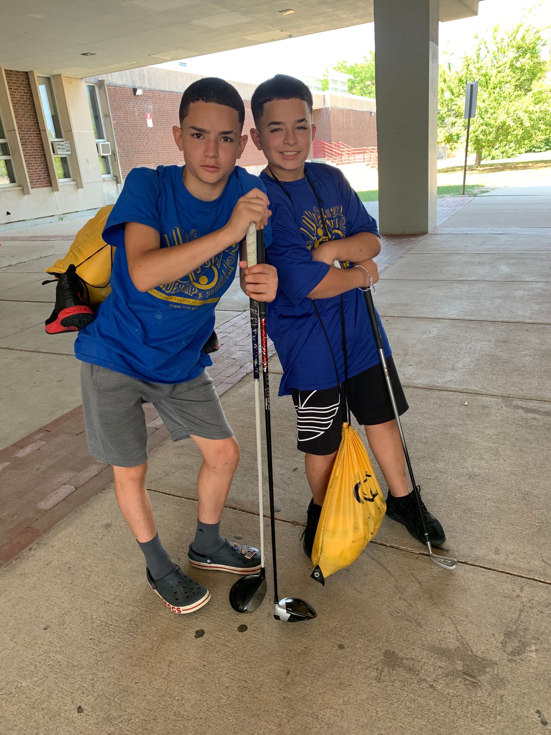 Two young boys standing next to each other holding hockey sticks