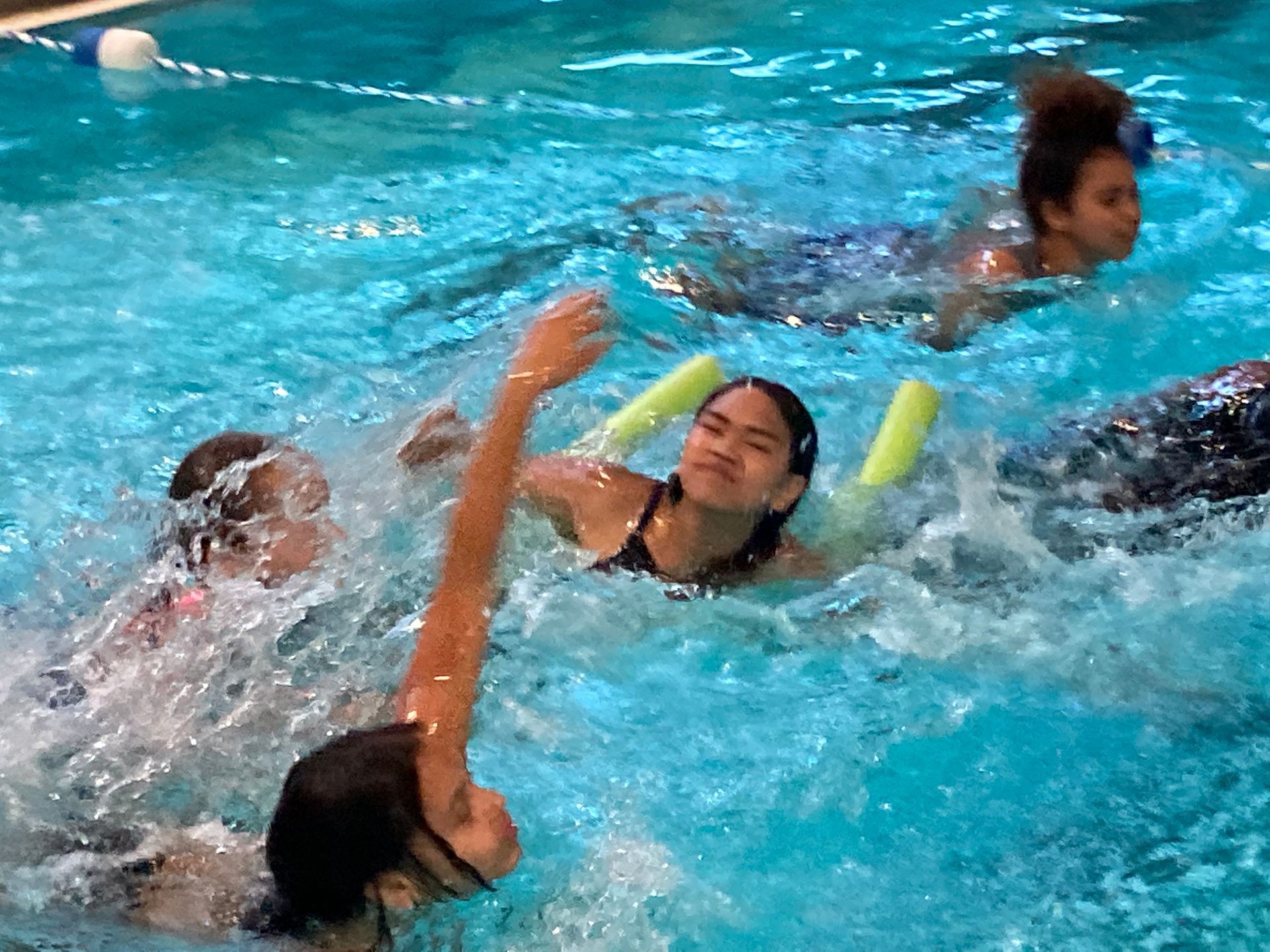 A group of children are swimming in a swimming pool.