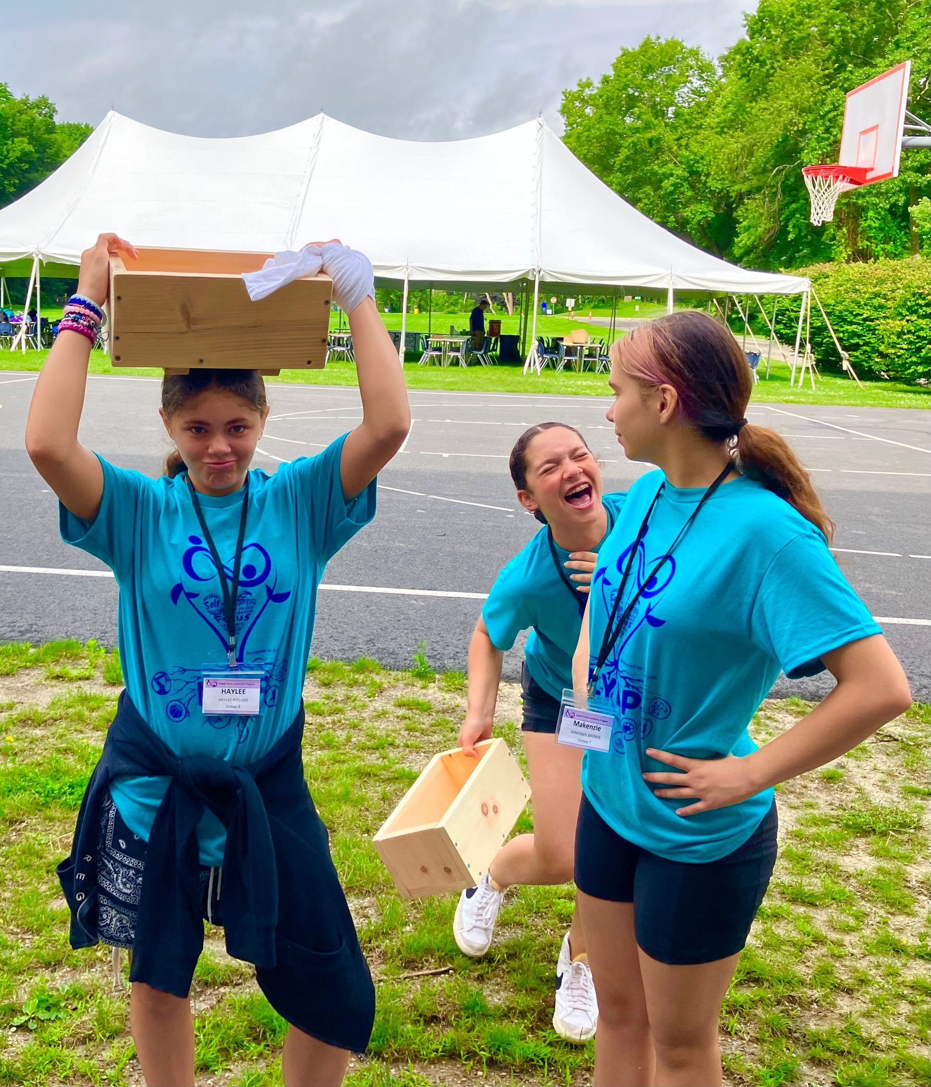 A woman in a blue shirt is holding a box on her head