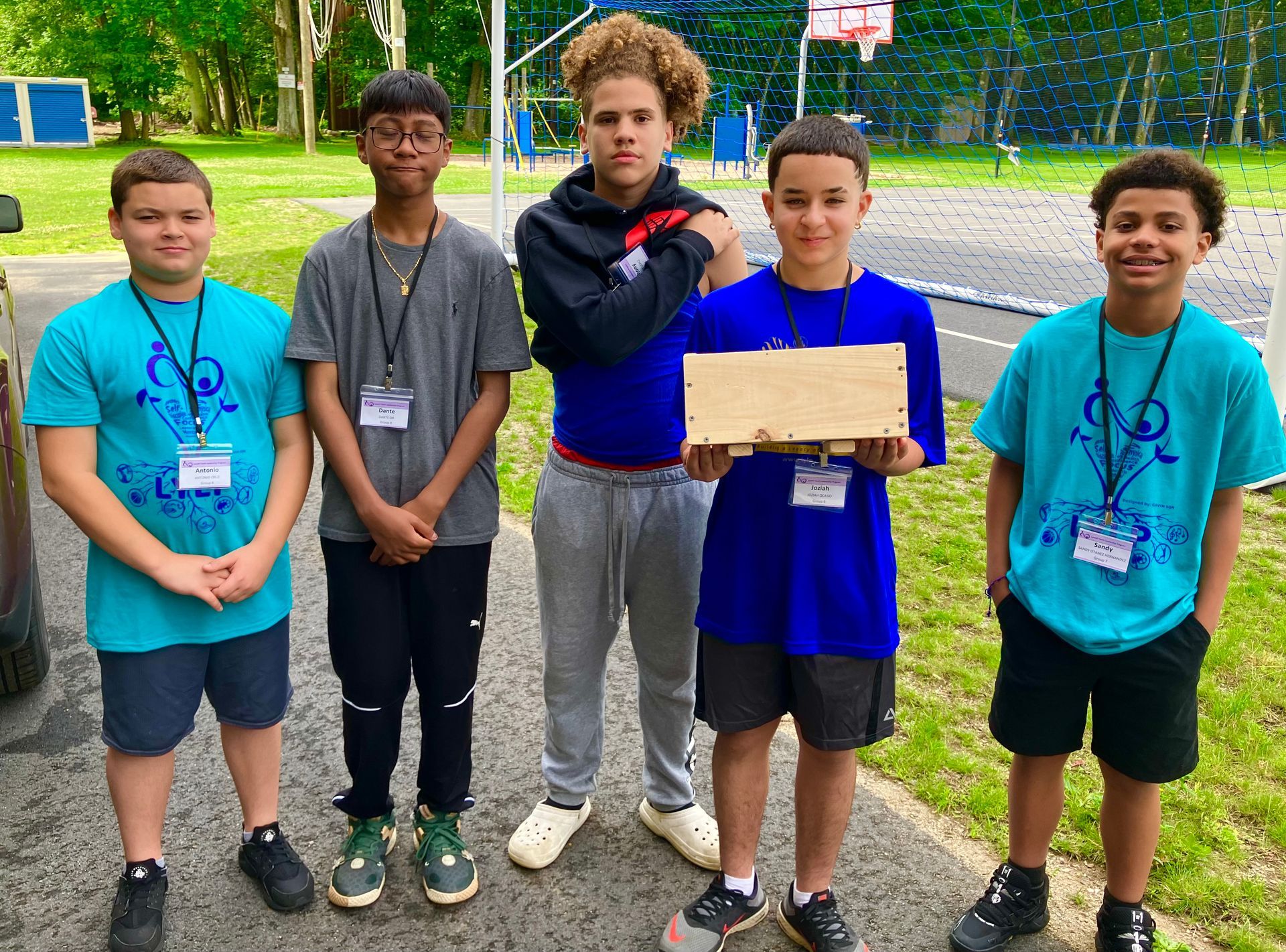 A group of young men standing next to each other holding a piece of wood