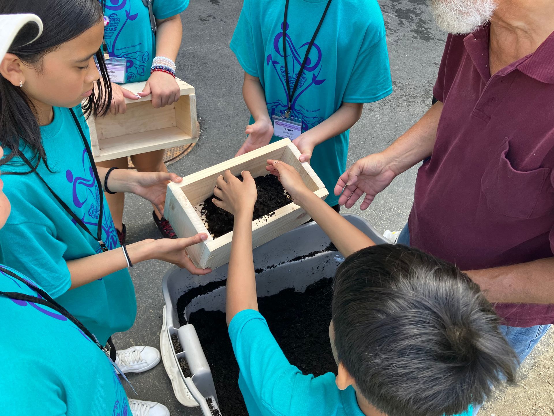 A group of children are looking at a box of dirt.