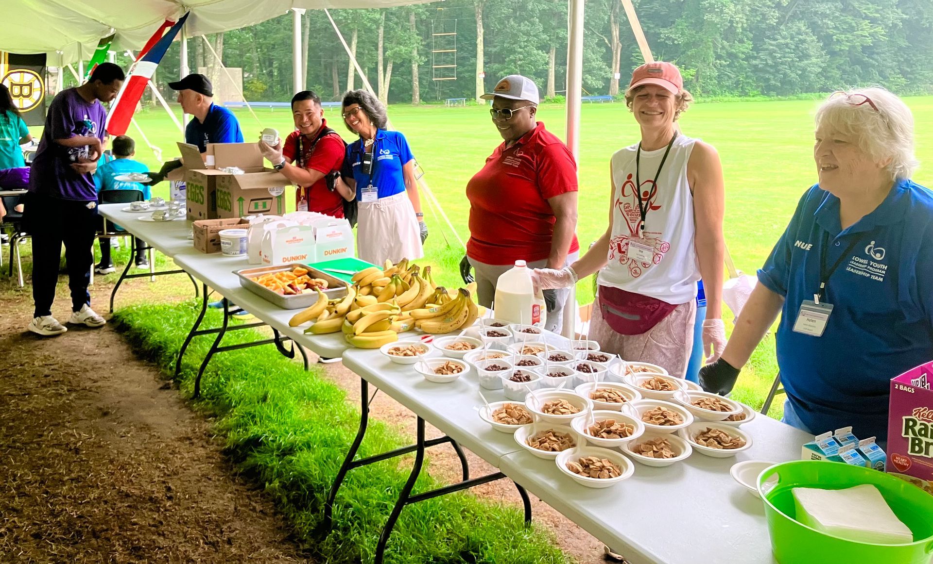 A group of people are standing around a table filled with food.