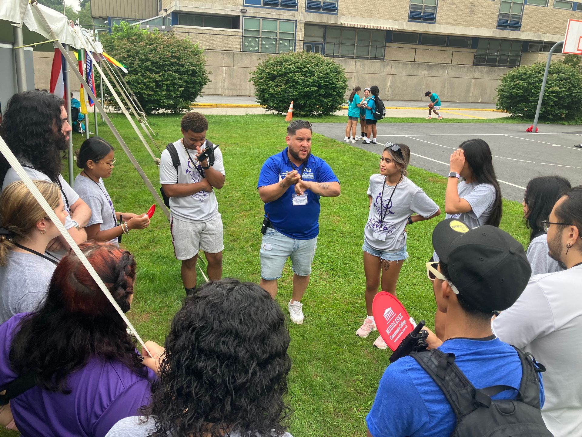 A group of people are standing in a circle in the grass.