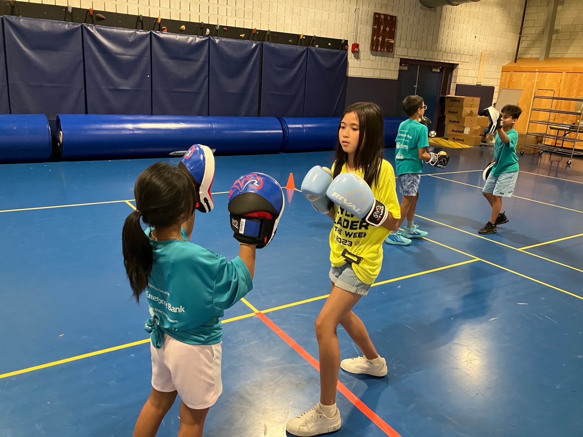 A group of young girls are practicing boxing in a gym.