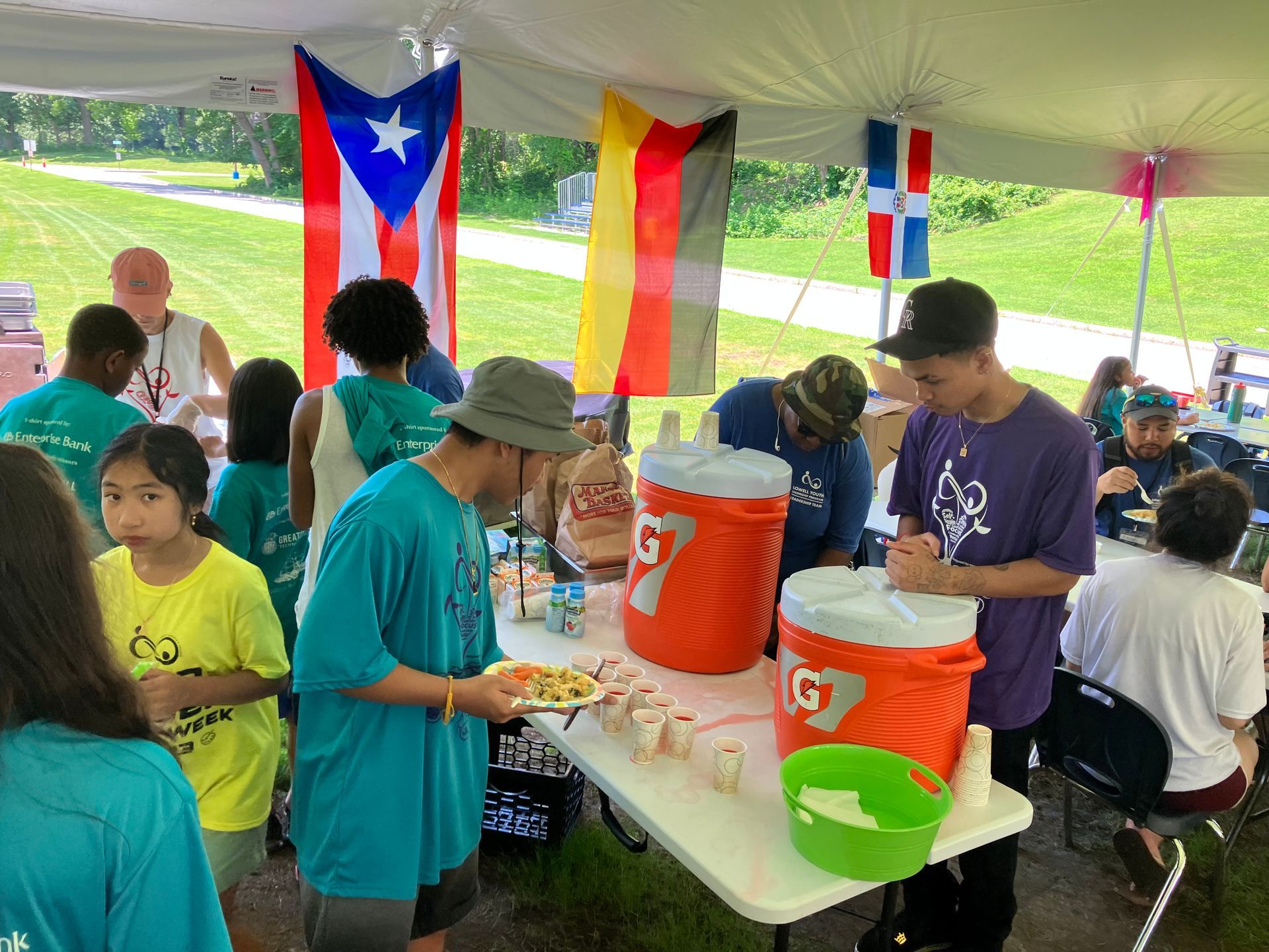 A group of people are standing around a table under a tent.