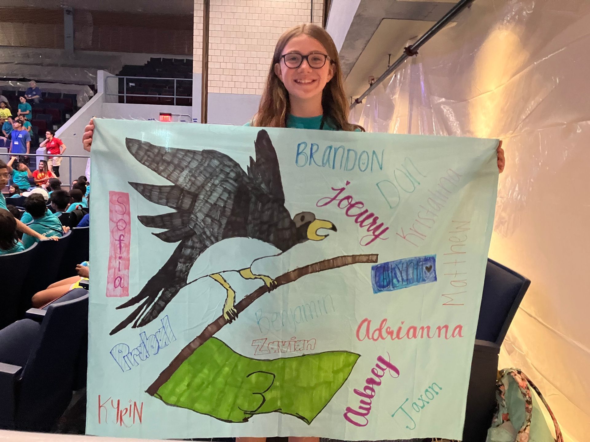 A girl is holding a drawing of an eagle on a branch.