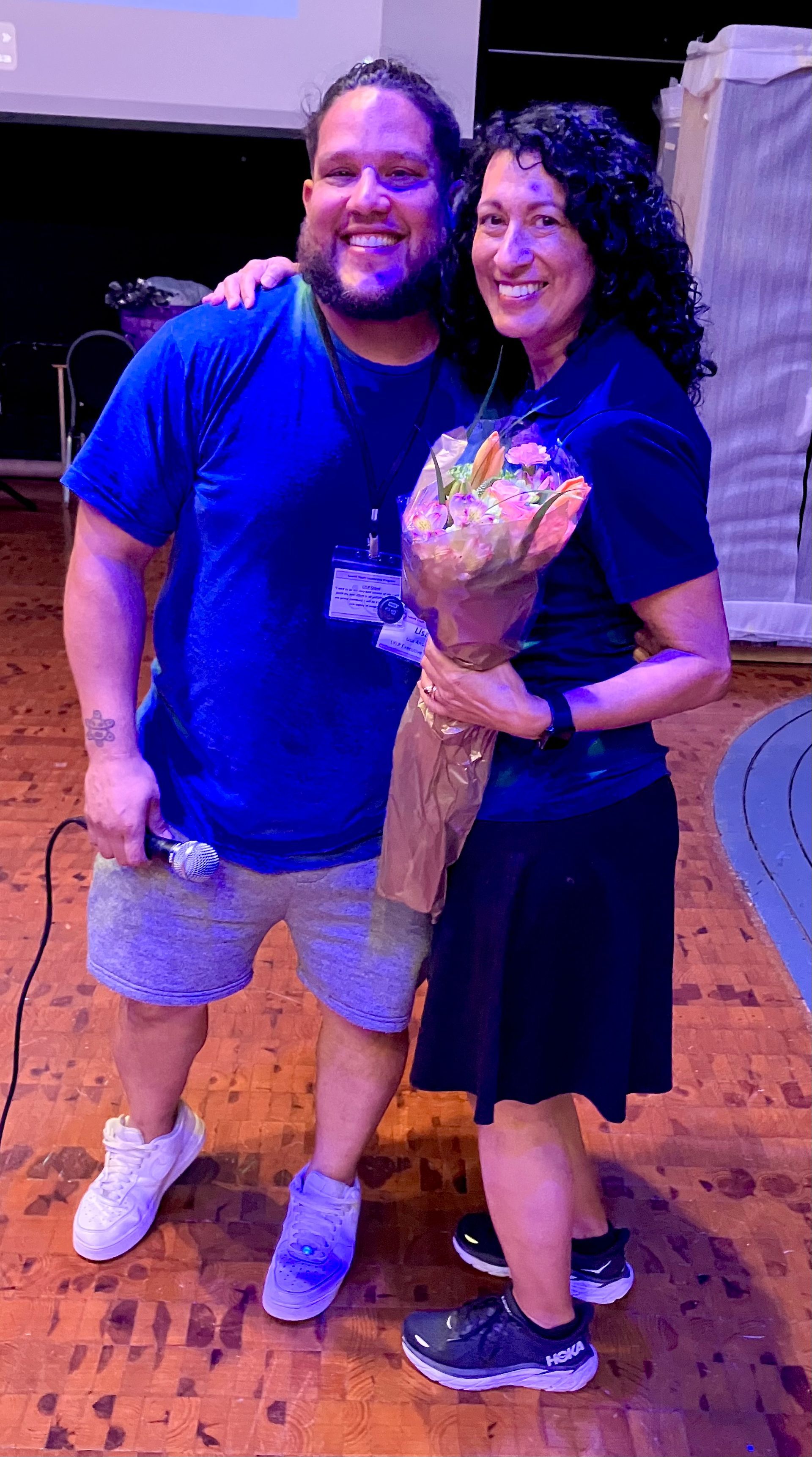 A man and a woman are standing next to each other holding a bouquet of flowers.