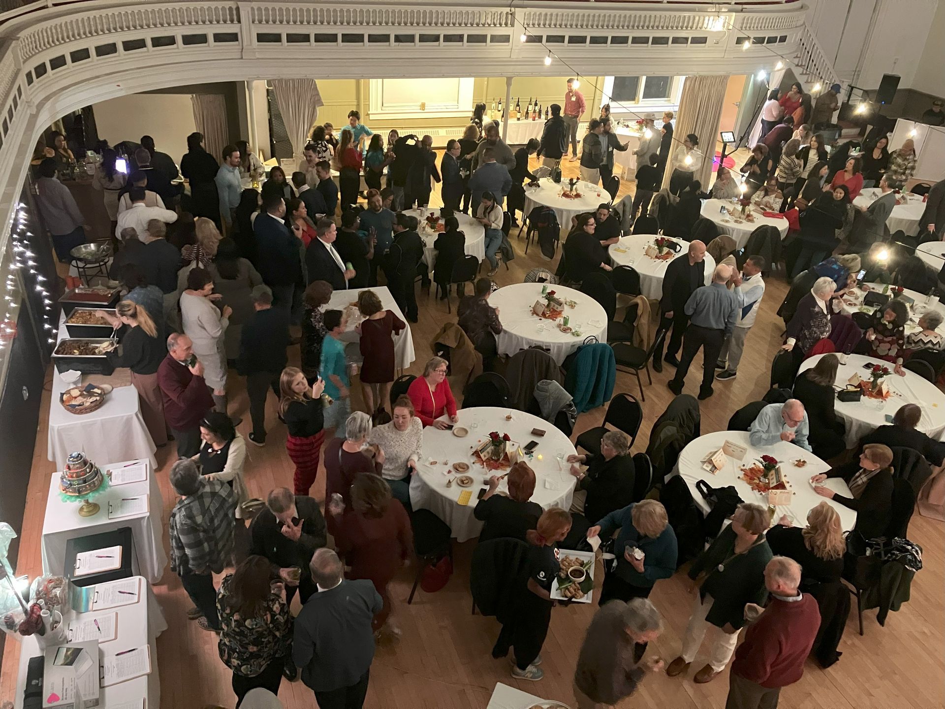 A large group of people are standing around tables in a room.