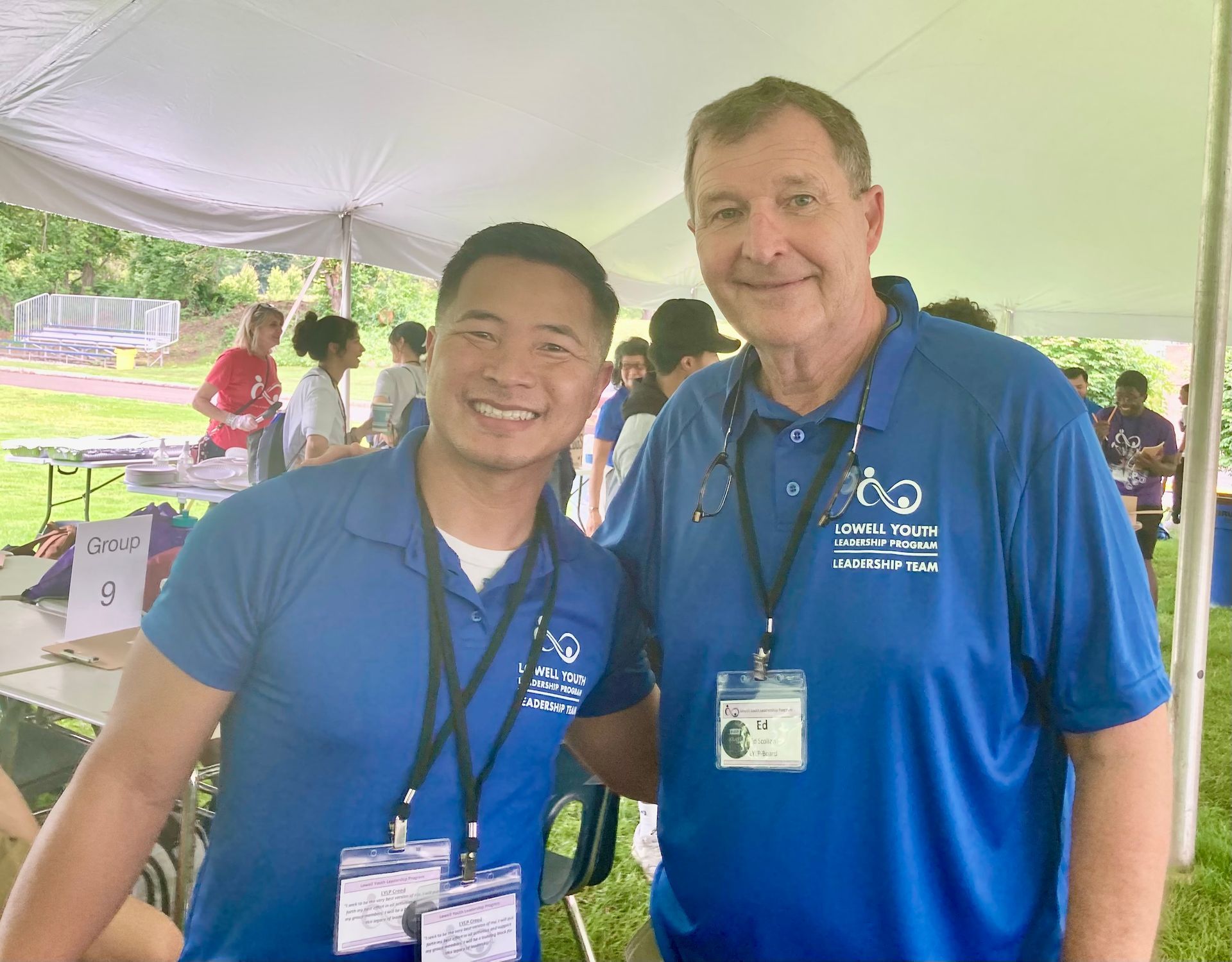 Two men are posing for a picture under a tent.