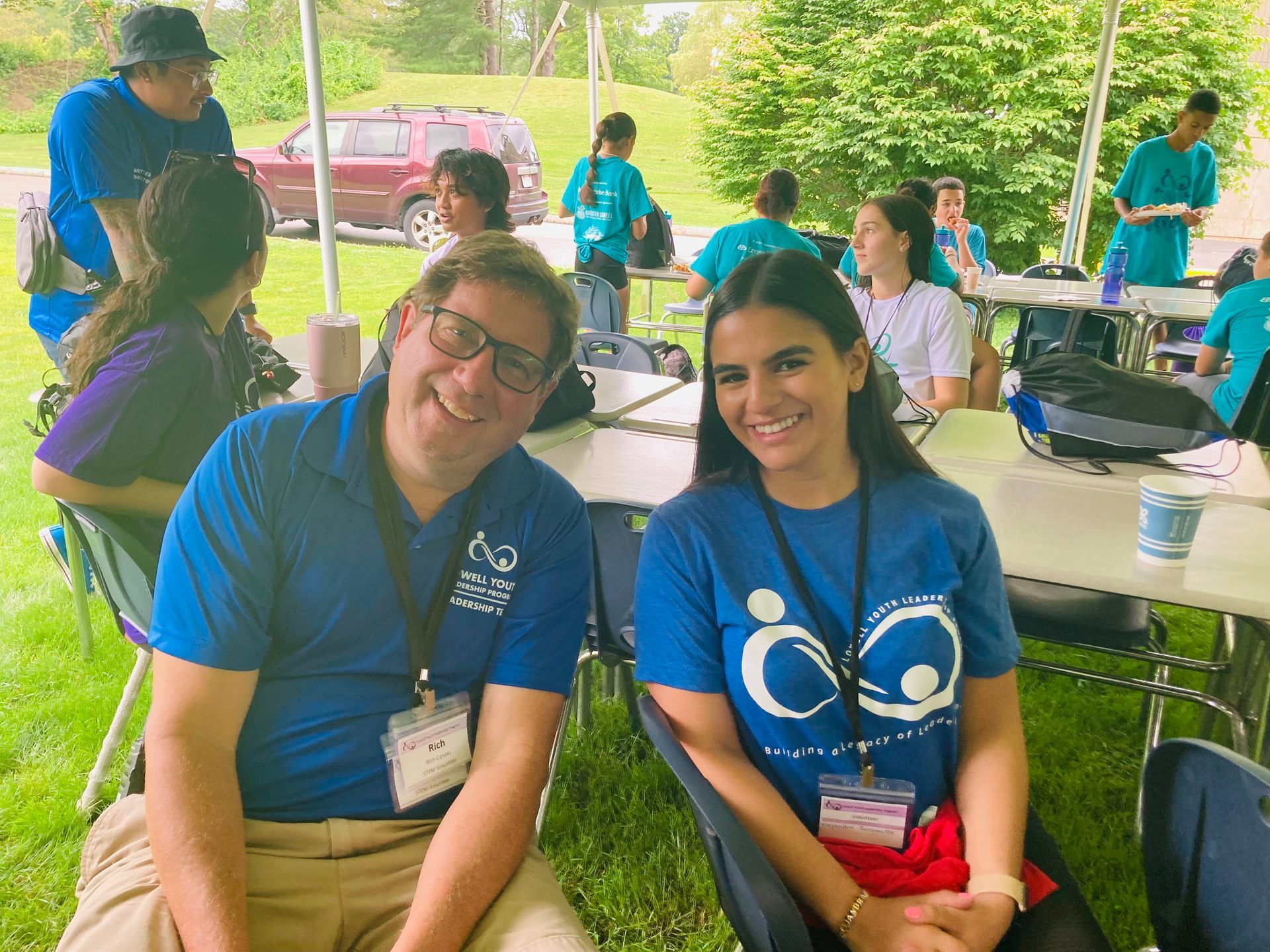 A man and a woman are posing for a picture while sitting under a tent.