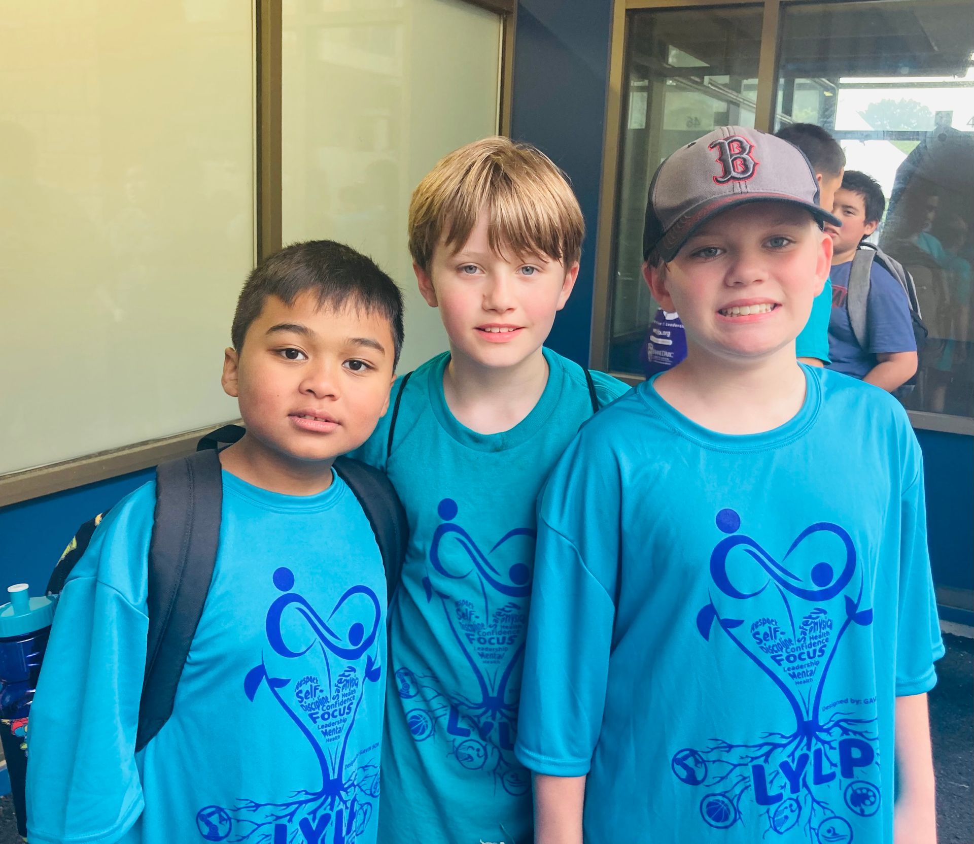 Three young boys wearing blue shirts with the letter b on them