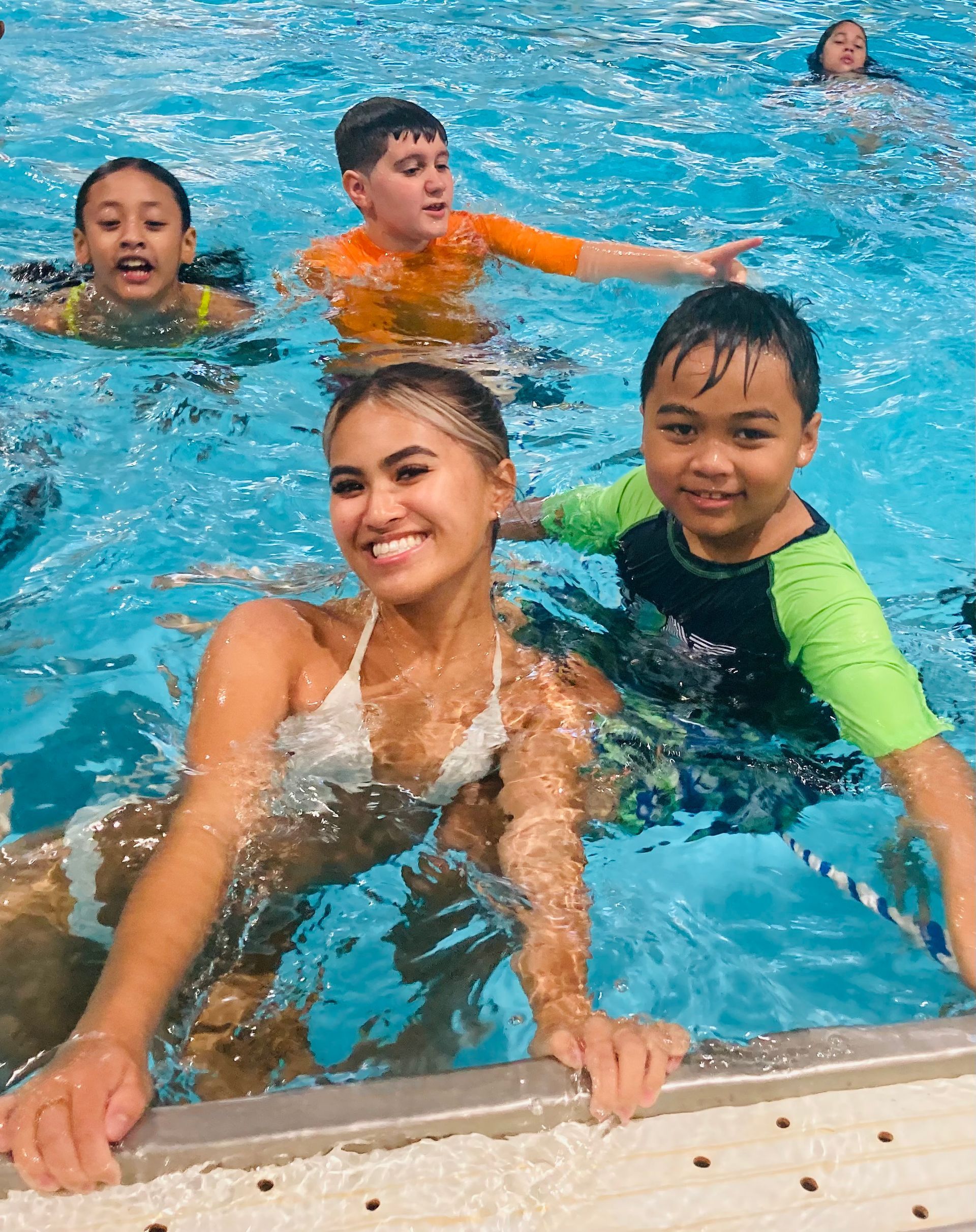 A group of children are swimming in a swimming pool.