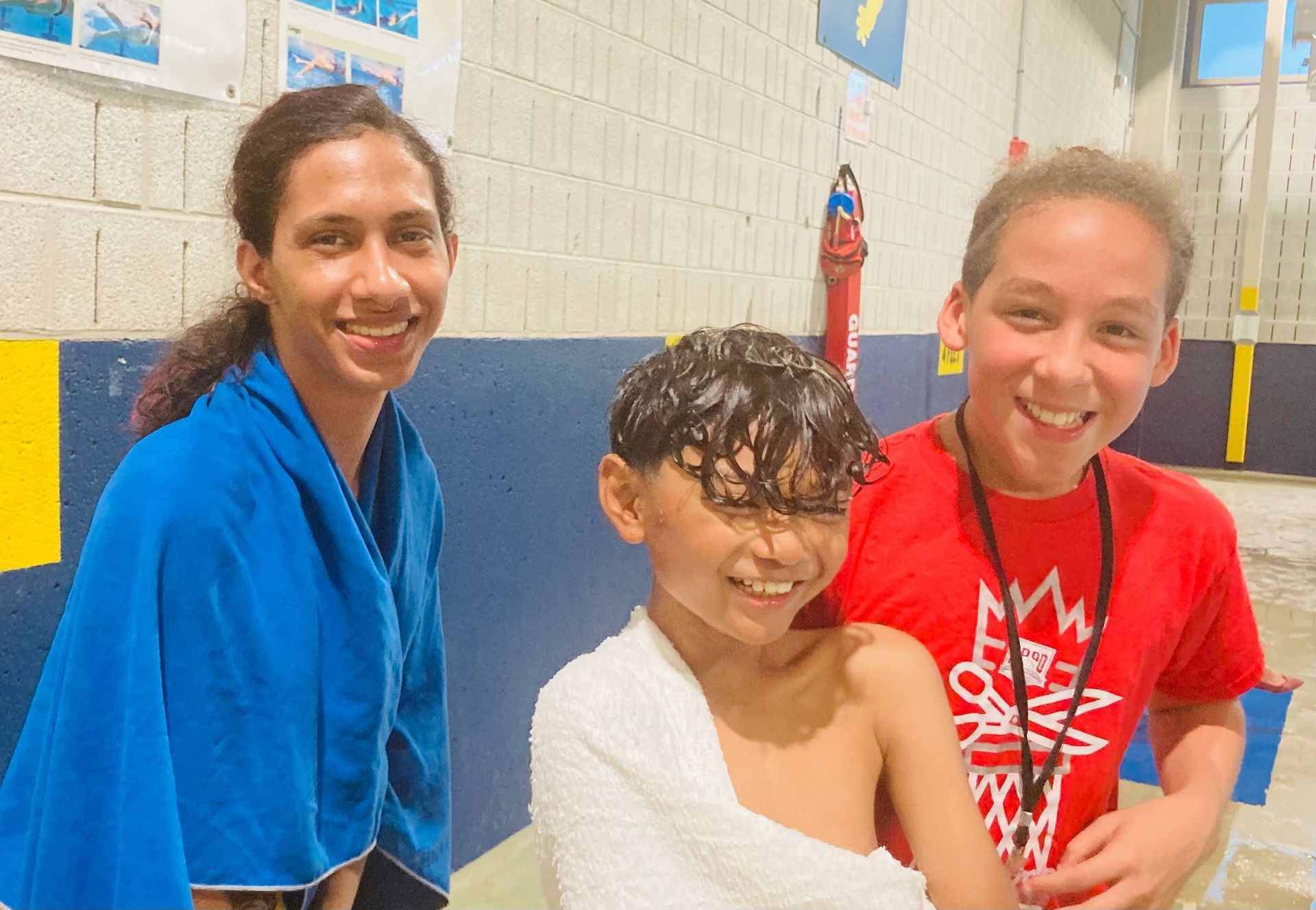 A woman and two girls are standing next to a boy wrapped in a towel.