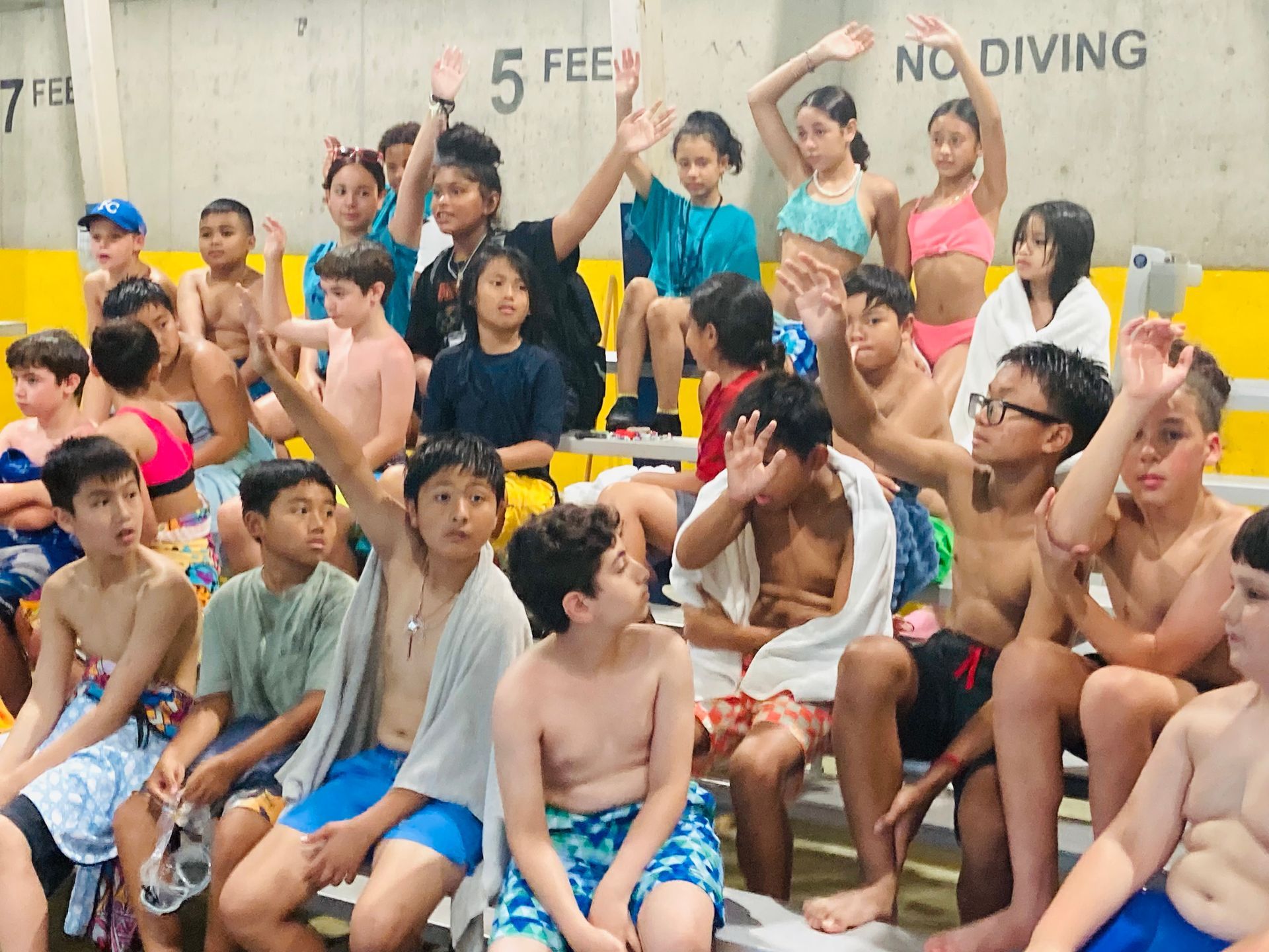 A group of children are sitting in front of a sign that says no diving