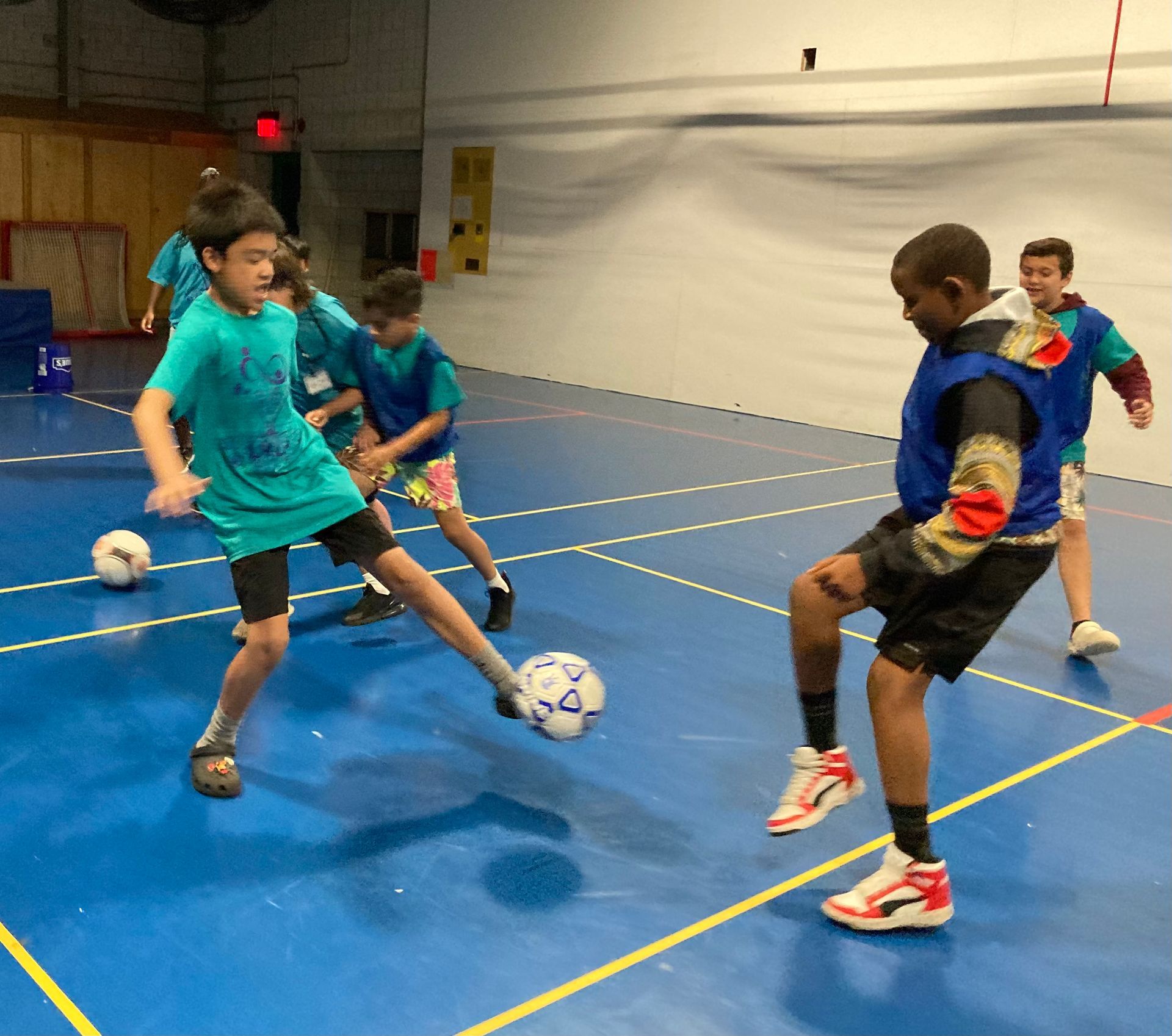 A group of young boys are playing soccer in a gym.