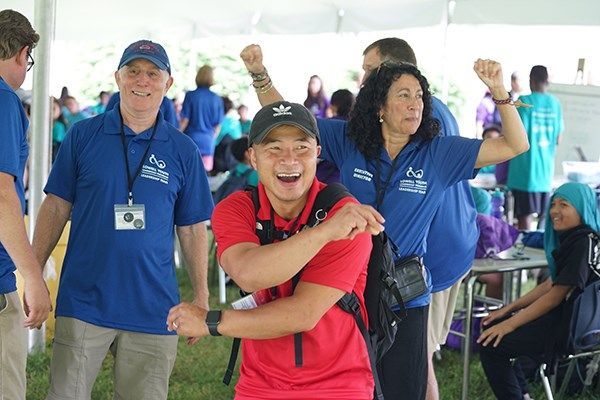 A group of people wearing blue shirts are standing under a tent.
