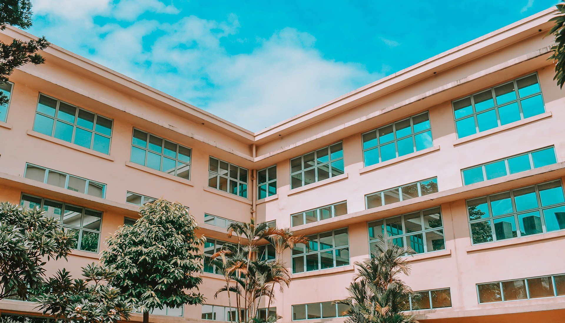 A large building with a lot of windows and trees in front of it