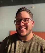 A man with a beard and glasses is smiling for the camera.