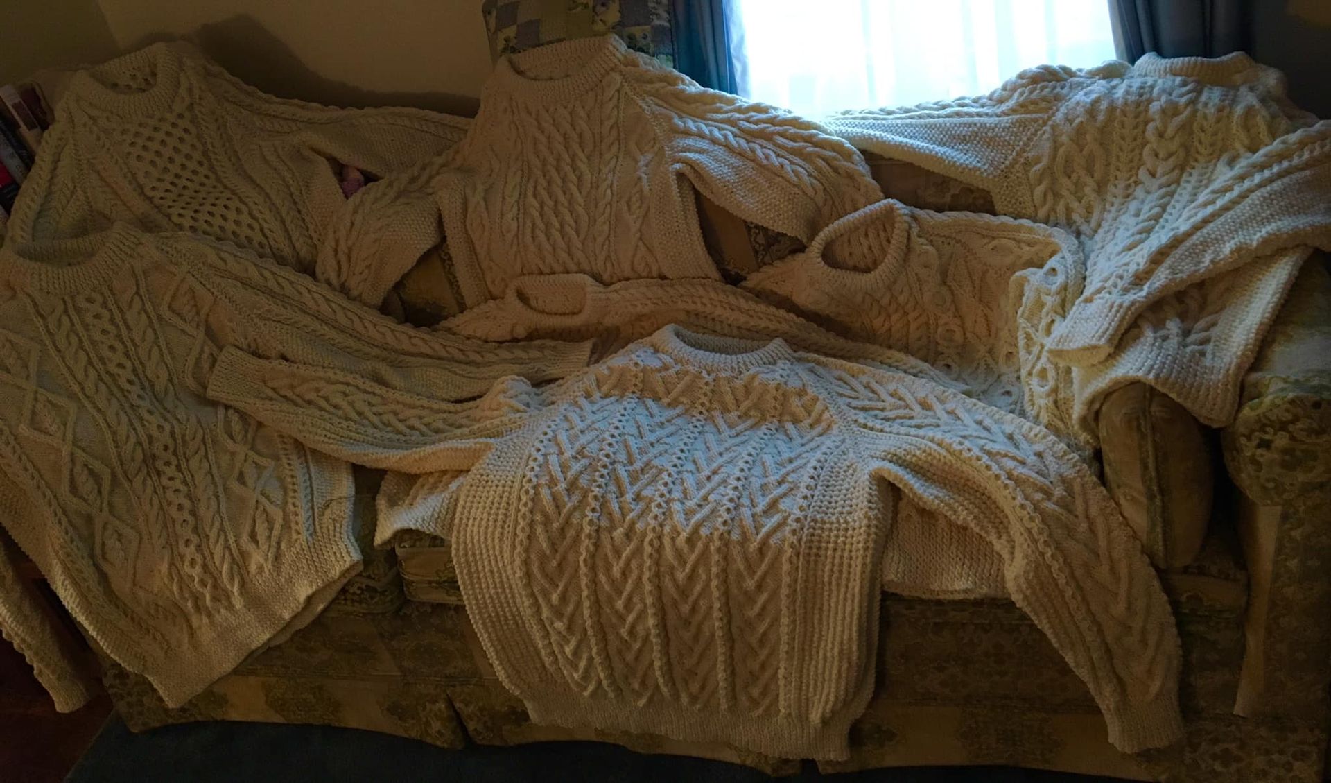 A couch covered in sweaters and blankets in a living room.