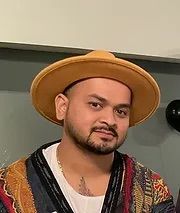 A man with a beard is wearing a hat and a sweater.