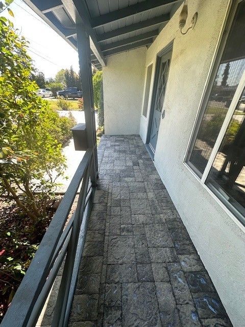 Narrow porch with stamped concrete flooring, gray railings, and a gray door.