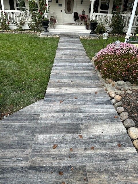 Stone path leading to a white house with grass on either side, and flower bushes.