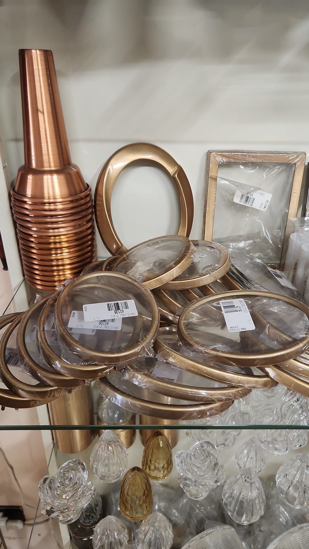 Vasi decorativi in ​​metallo, anelli d'oro e oggetti in vetro esposti sugli scaffali di un negozio.
