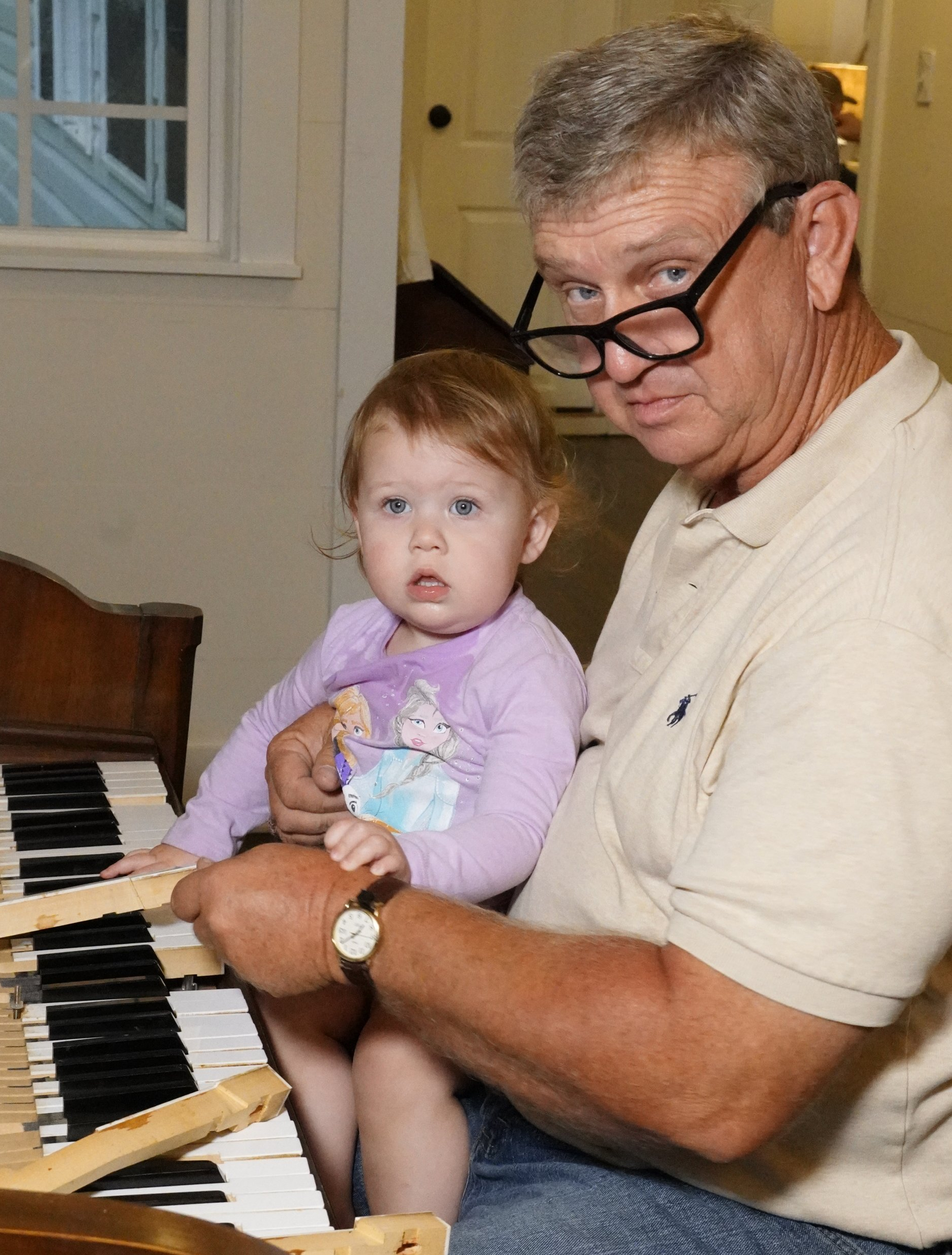A man is holding a baby while playing a piano