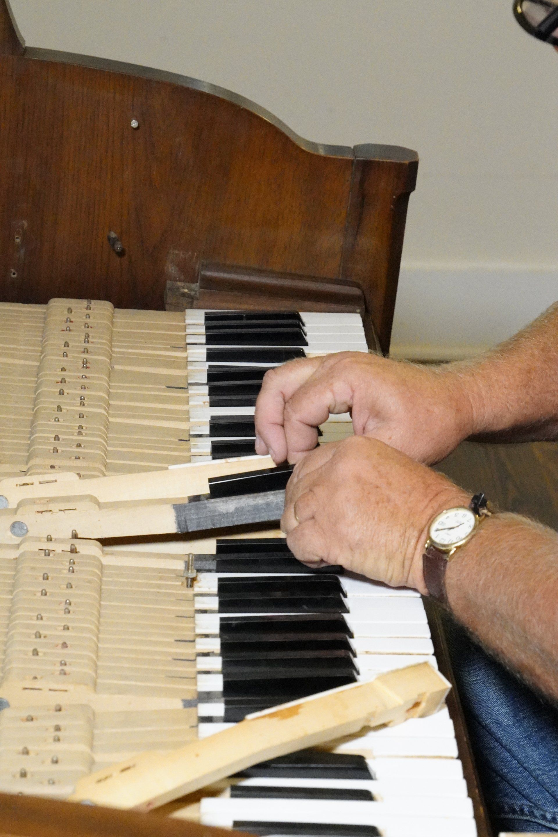 A man wearing a watch is working on a piano