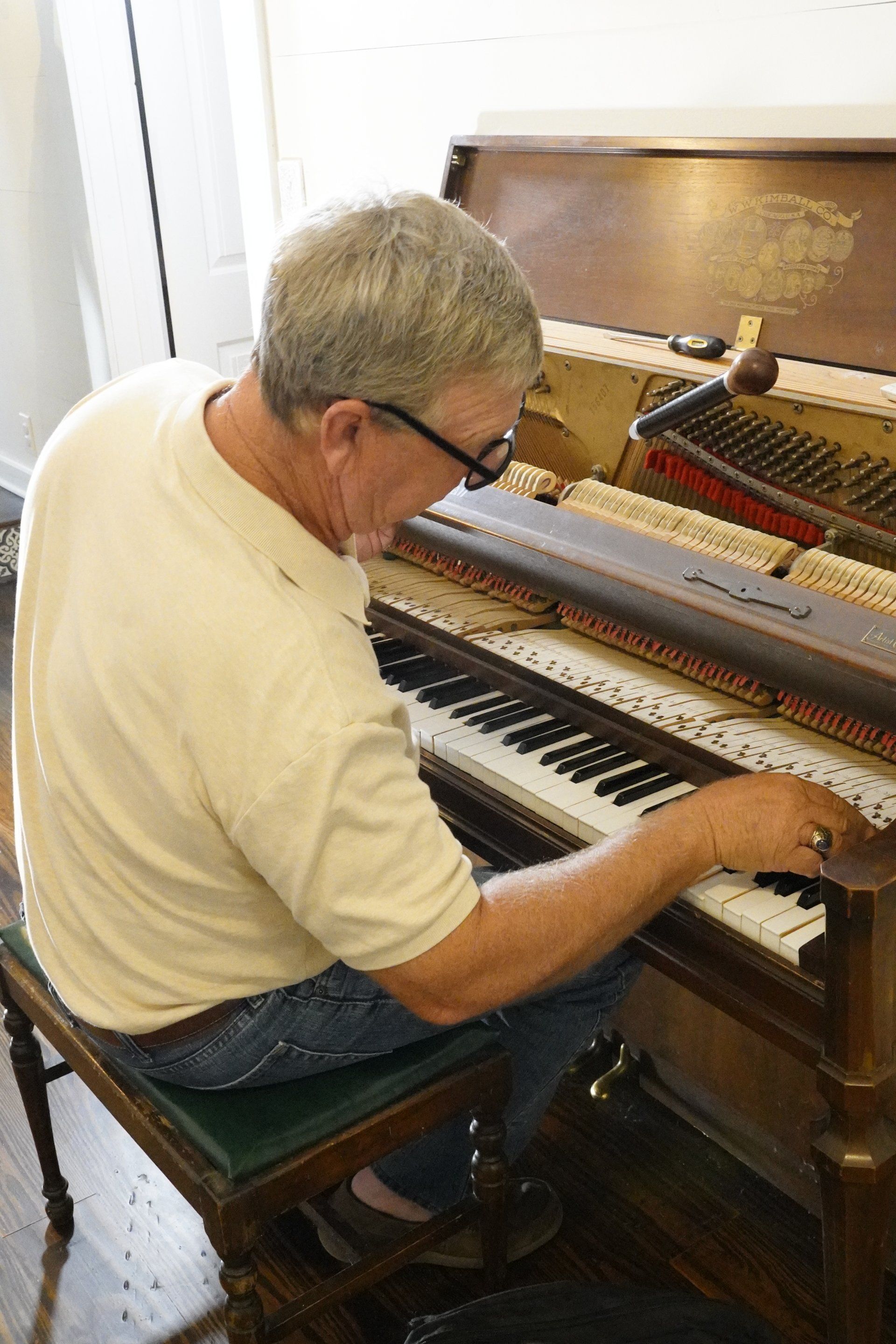 A man is sitting on a bench playing a piano.
