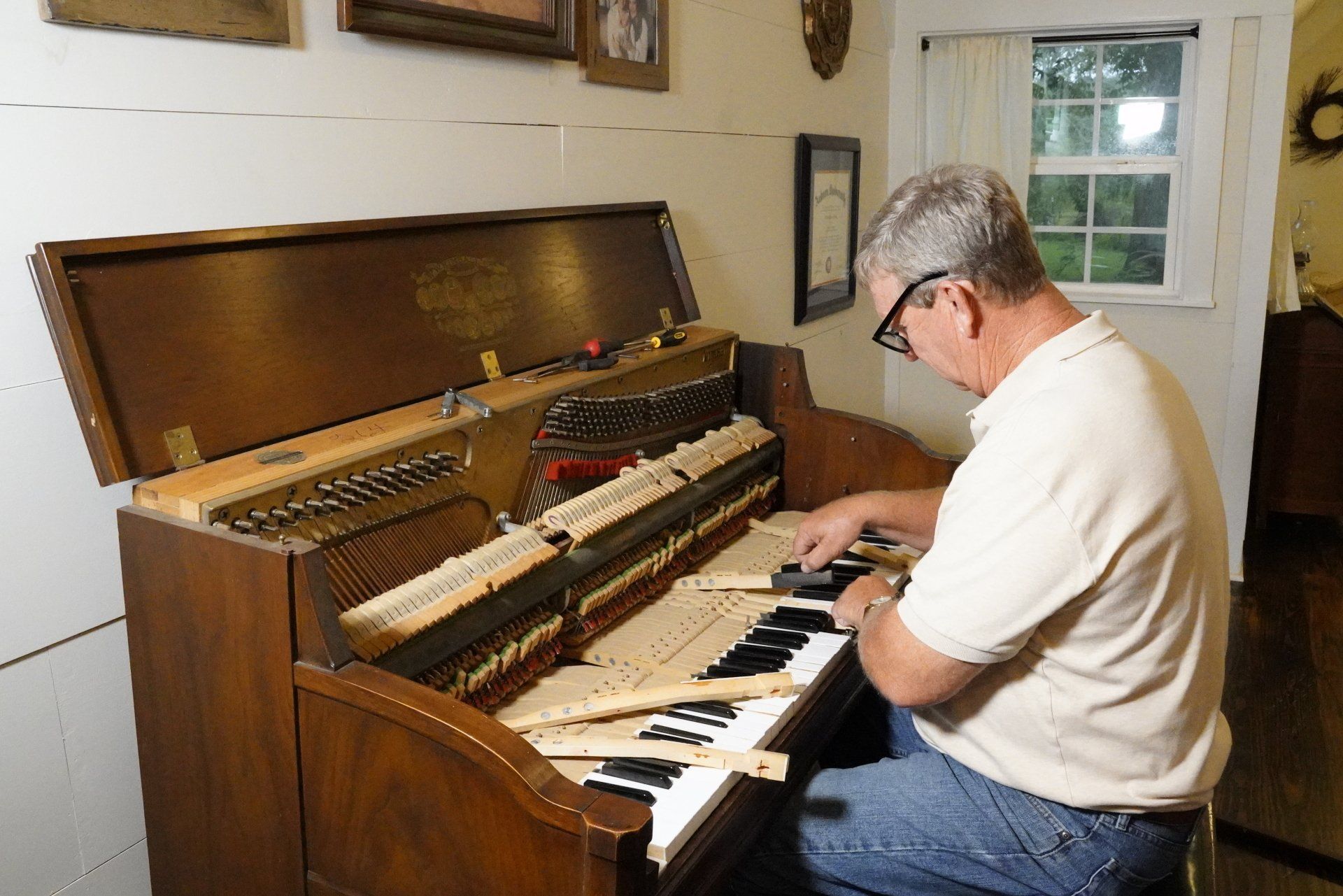 A man is working on a piano in a living room