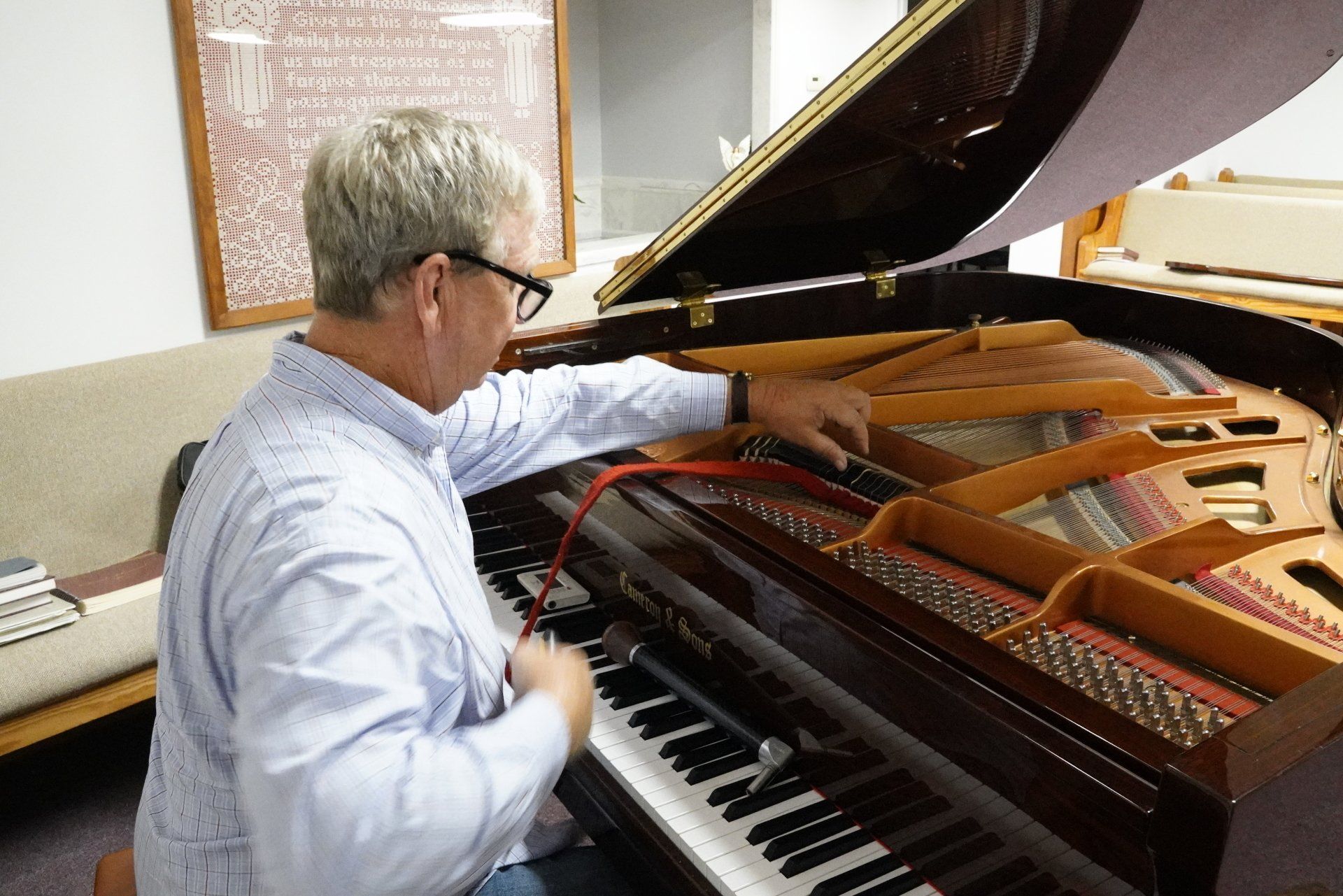 A man is playing a piano with the lid open.