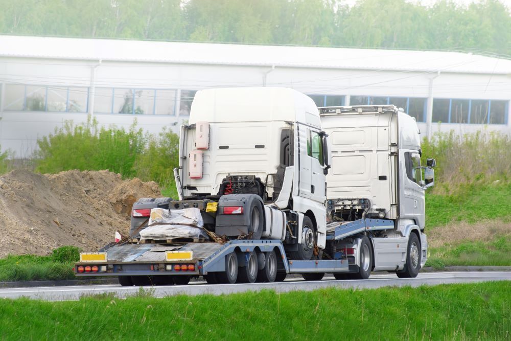 Two Semi Trucks Are Driving Down a Road with A Trailer — Easylift Towing NSW Pty Ltd In Beresfield, QLD