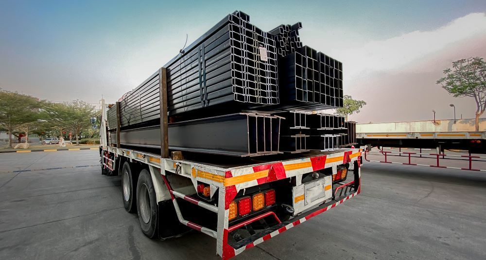 A Truck Is Carrying a Stack of Steel Beams on The Back of It — Easylift Towing NSW Pty Ltd In Beresfield, QLD