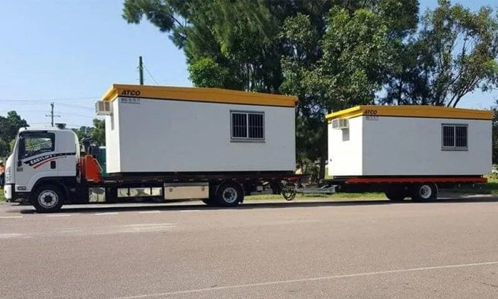 A Truck Is Pulling a Trailer with Two Houses on It — Easylift Towing NSW Pty Ltd In Swansea, QLD