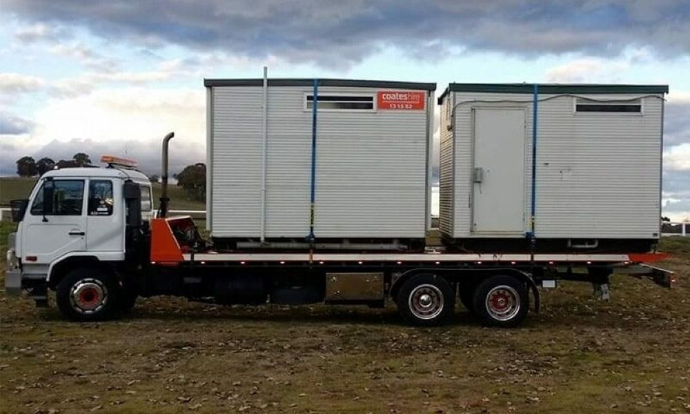 A Semi Truck Is Driving Down a Highway Next to A Forest — Easylift Towing NSW Pty Ltd In Cessnock, QLD
