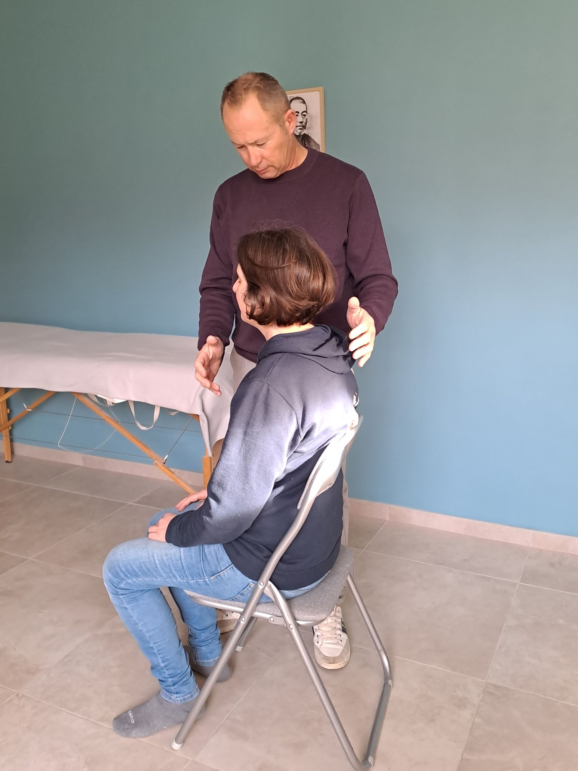un homme se tient à côté d' une femme assise sur une chaise .