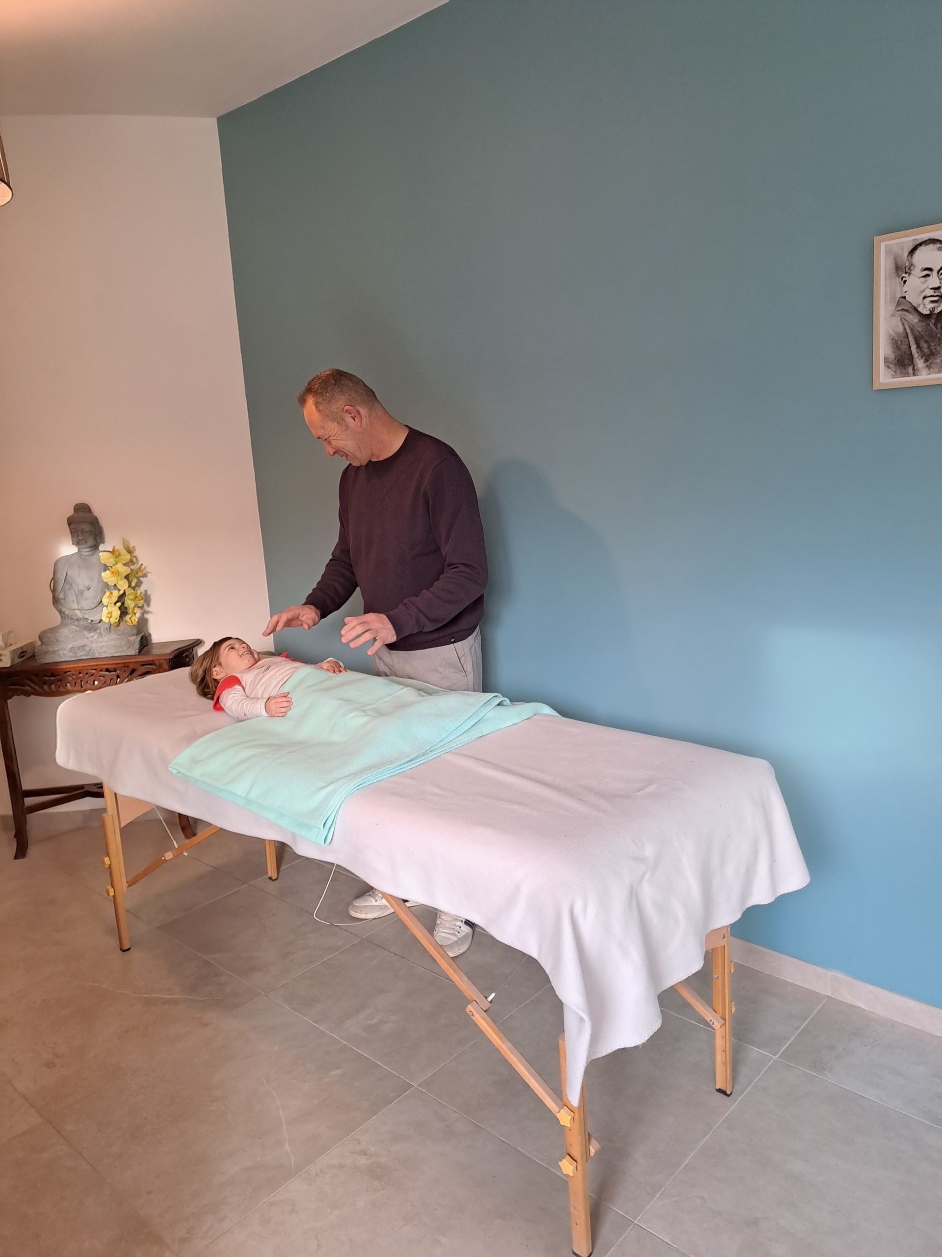 un homme masse un bébé allongé sur une table de massage .