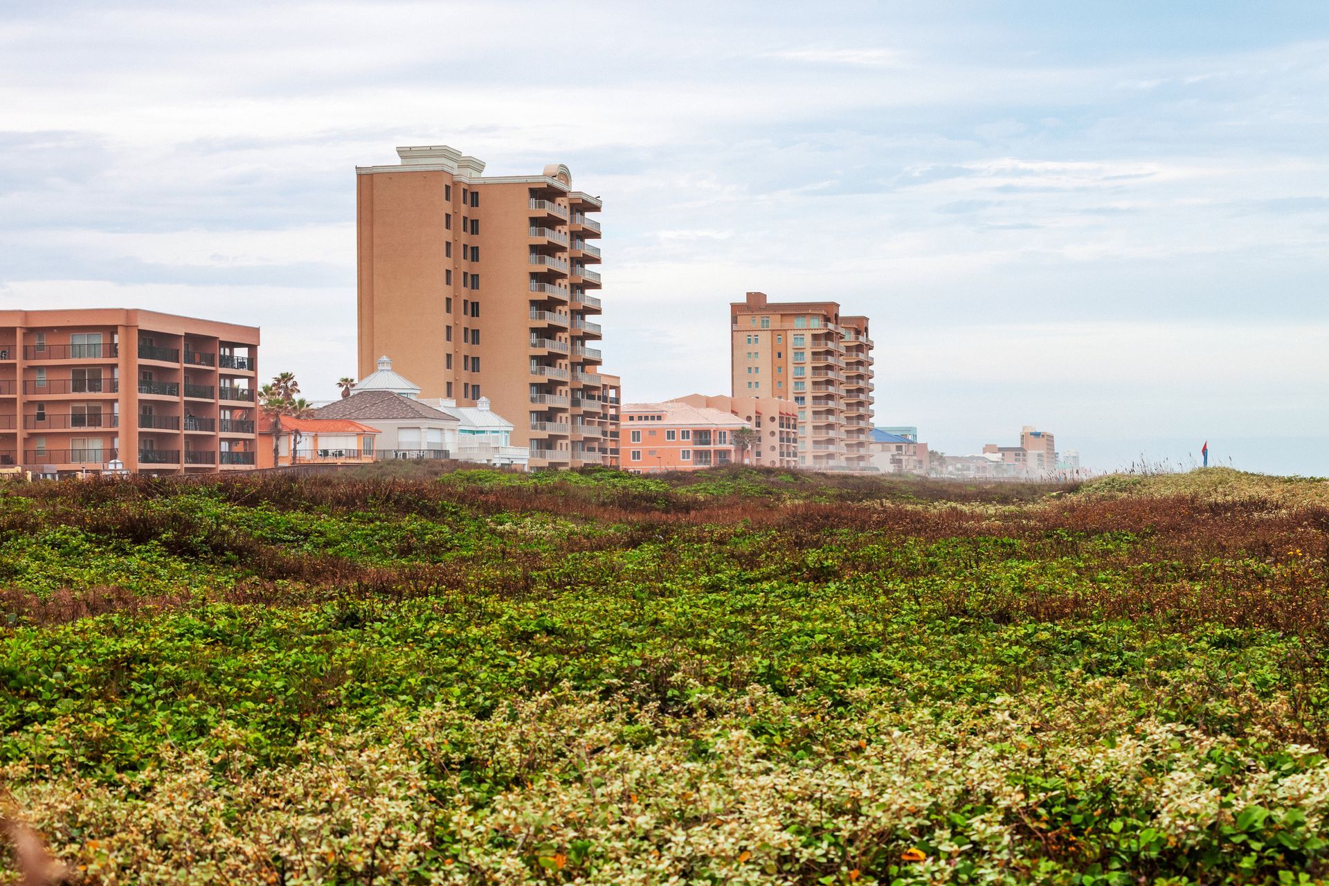 There are a lot of buildings in the background and a field in the foreground.